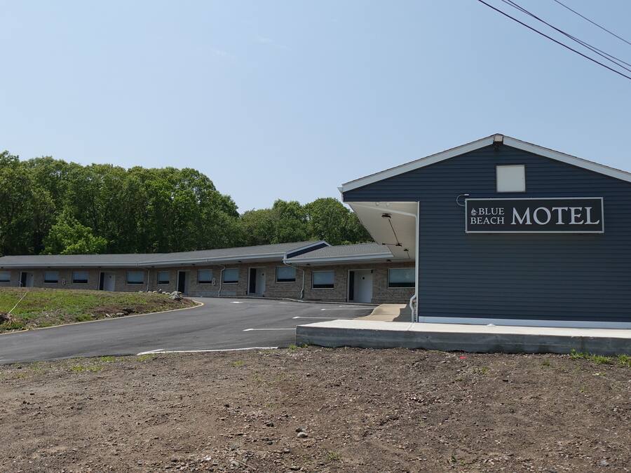 Un motel con un cartel que dice "Blue Beach Motel" y un edificio sencillo de una sola planta con techo plano.