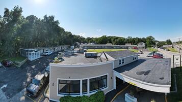 A motel with a parking lot, a small building with a curved roof, and a large building in the background.