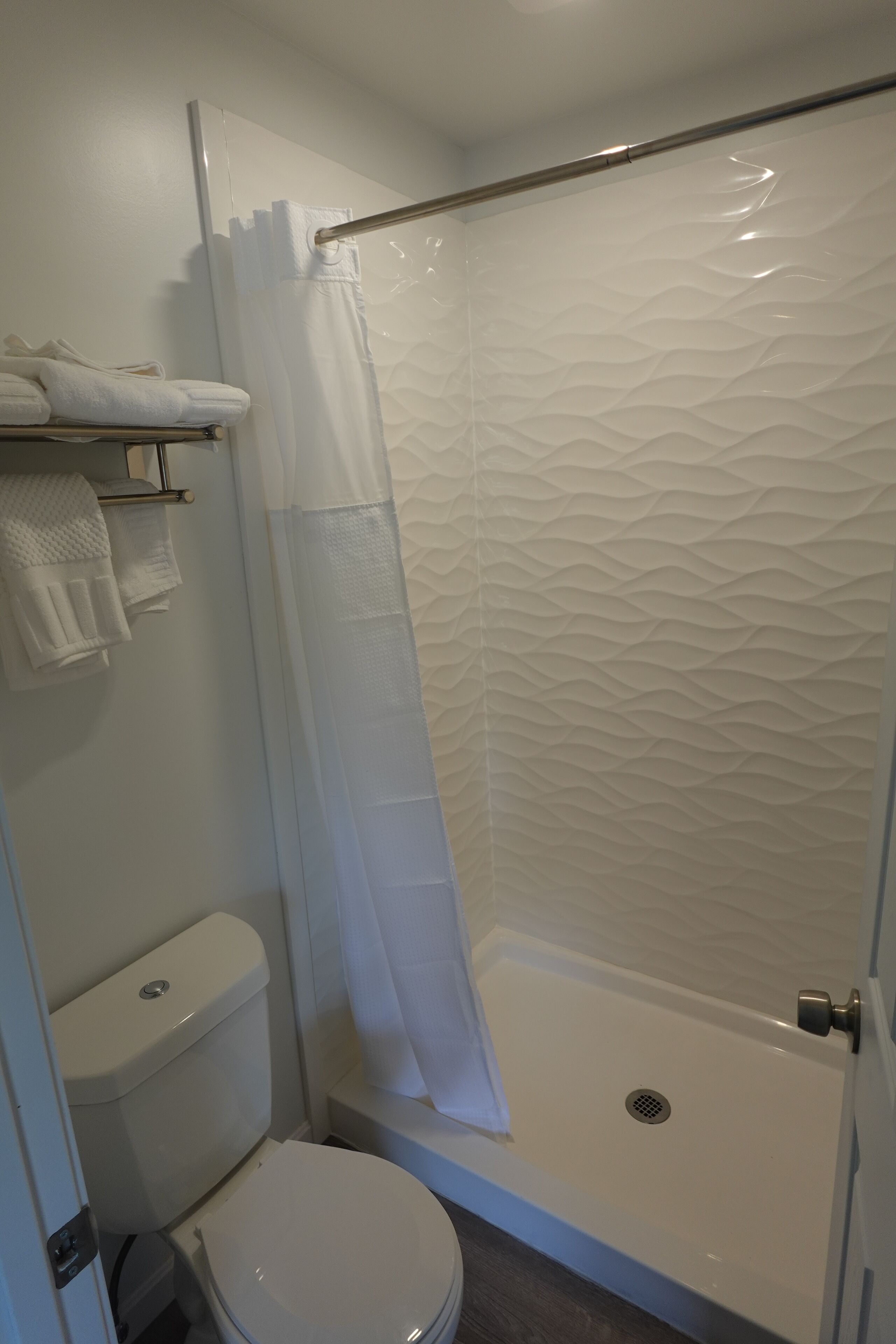 Ein Badezimmer mit Dusche, Toilette und Handtuchhalter.