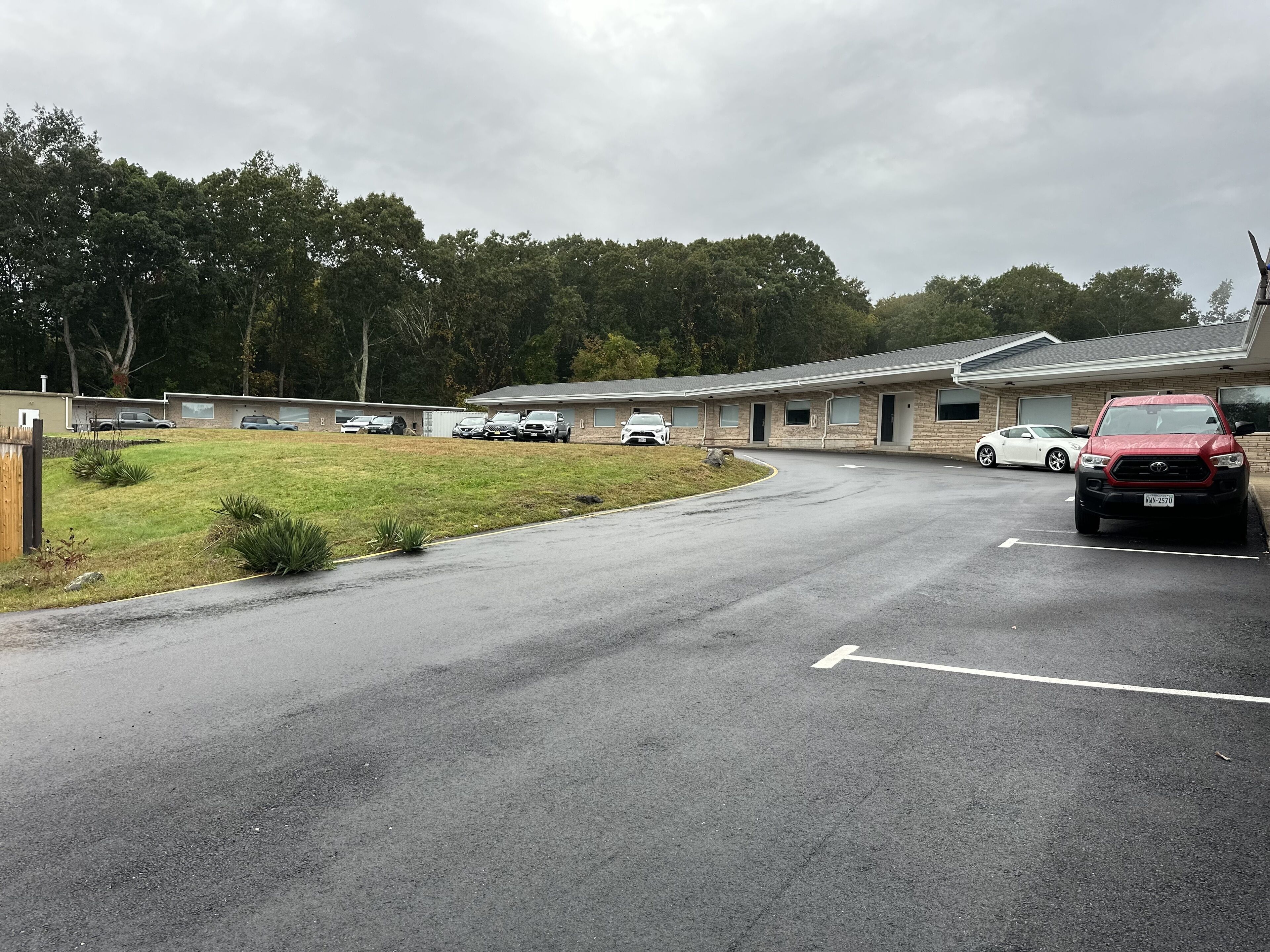 A motel with a parking lot, a grassy area, and a building with a brick facade.