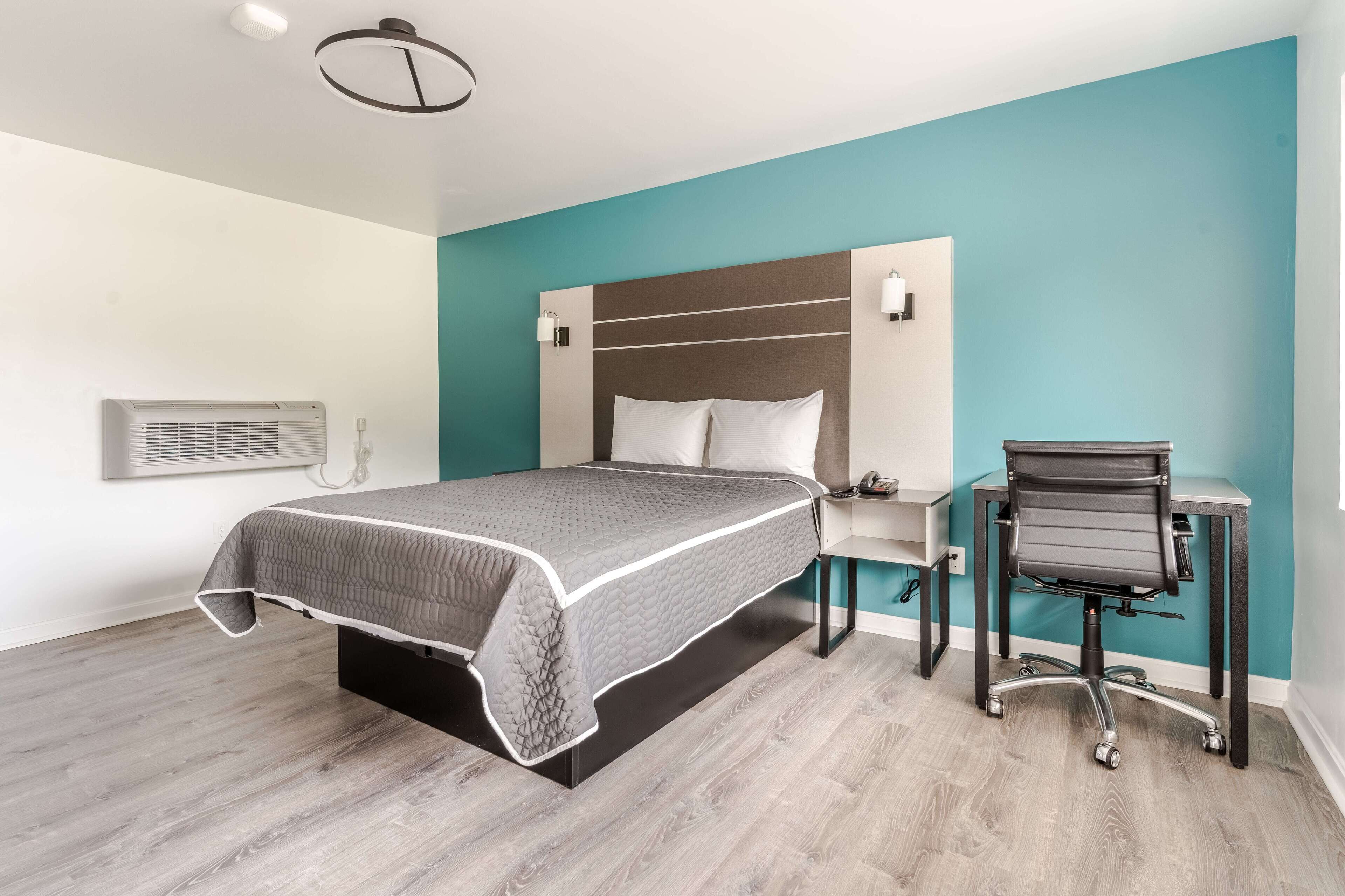 A modern bedroom with a bed, a desk, and a chair.