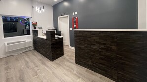 A reception area with a modern design, featuring a reception desk, a digital screen, and a wall-mounted elevator. - Blue Beach Motel (North Kingstown)
