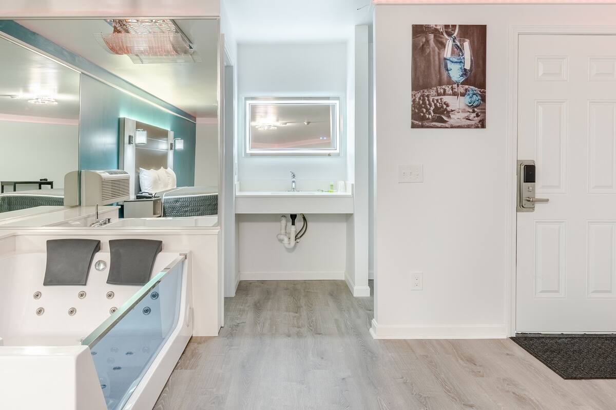 A modern bathroom with a large mirror, a vanity with a sink, and a bathtub.