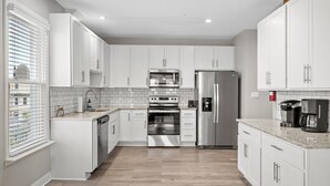 A modern kitchen with white cabinets, stainless steel appliances, and a tiled backsplash.