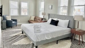 A bedroom with a bed, a chair, a desk, and a ceiling fan.