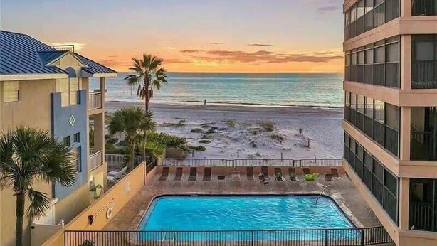 Un hôtel avec piscine, vue sur la plage et coucher de soleil.