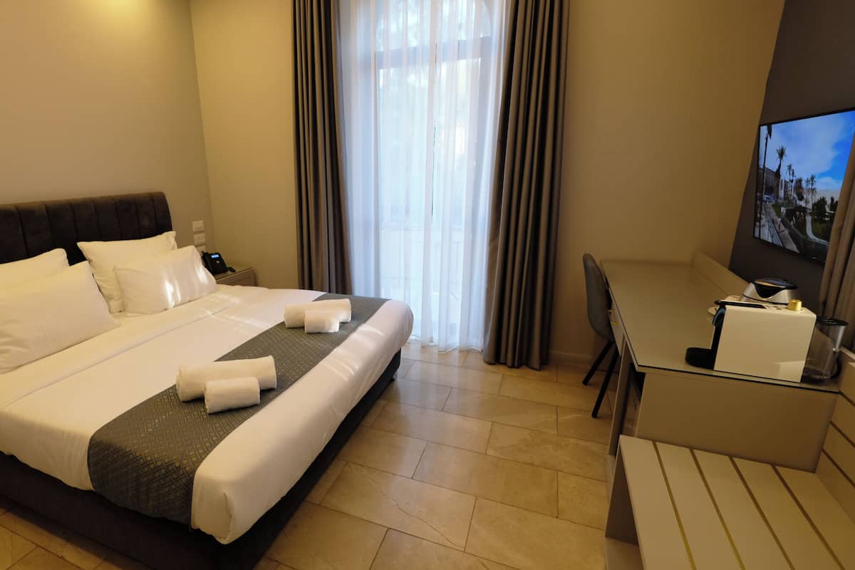 A hotel room with a large bed, a desk, and a television.