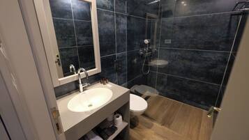 Ein modernes Badezimmer mit Waschbecken, Spiegel, Toilette und Duschbereich.