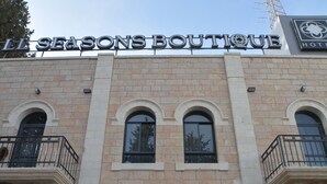 En byggnad med en skylt som visar texten "L'ESAGONS BOUTIQUE" och en hotelllogotyp. Byggnaden har en klassisk arkitektur med välvda fönster och balkonger.