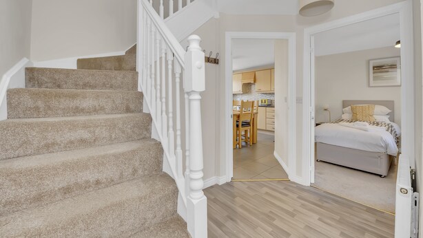 Un escalier mène à une chambre à coucher qui comprend un lit, un coin repas et une cuisine en arrière-plan.