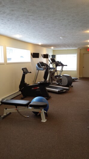 A gym with treadmills, an elliptical, and a bench.