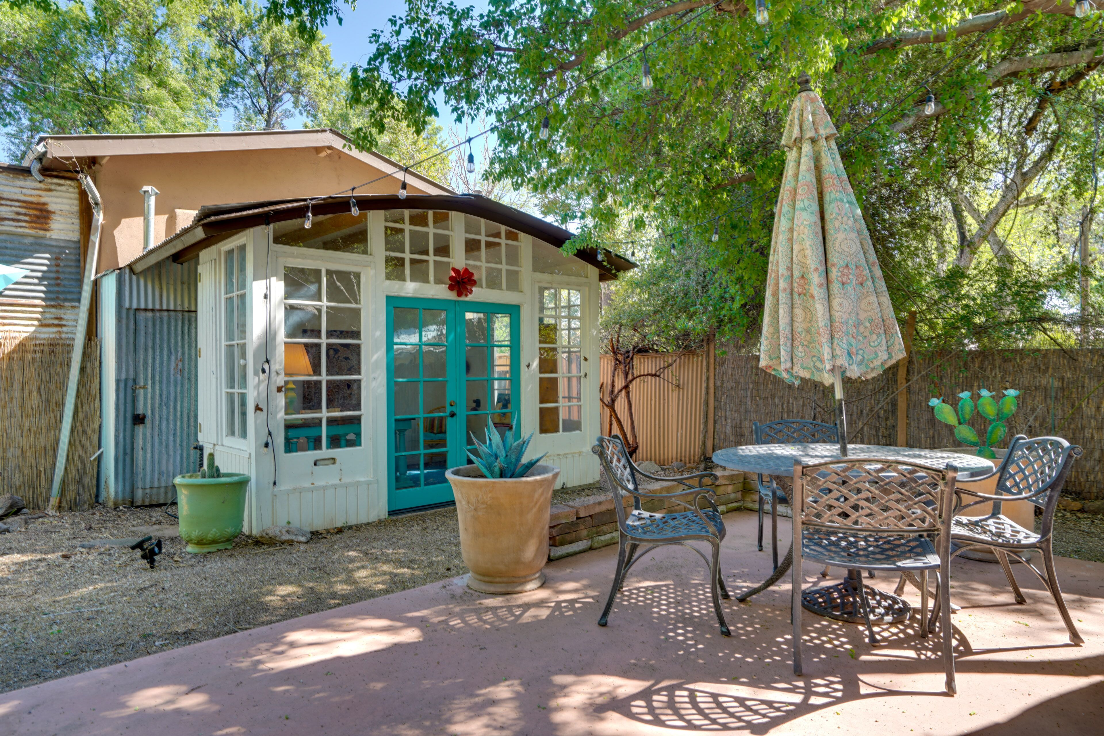 A patio area with a table and chairs, a potted plant, and a door with a decorative flower.