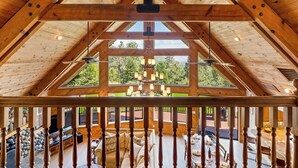 A high-ceilinged wooden interior with a view of a landscaped outdoor area.