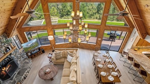 A spacious living area with a stone fireplace, a large beige sofa, and a dining table set for six.
