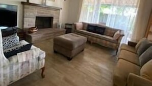 Een woonkamer met een open haard, een bank, een salontafel en een televisie.