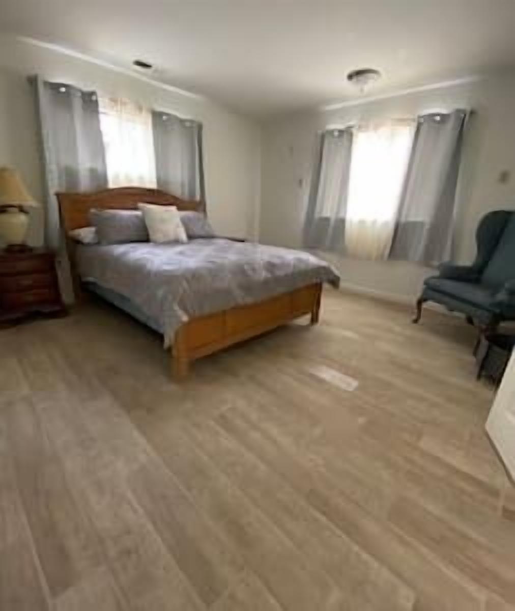A bedroom with a wooden bed, a chair, and a nightstand.