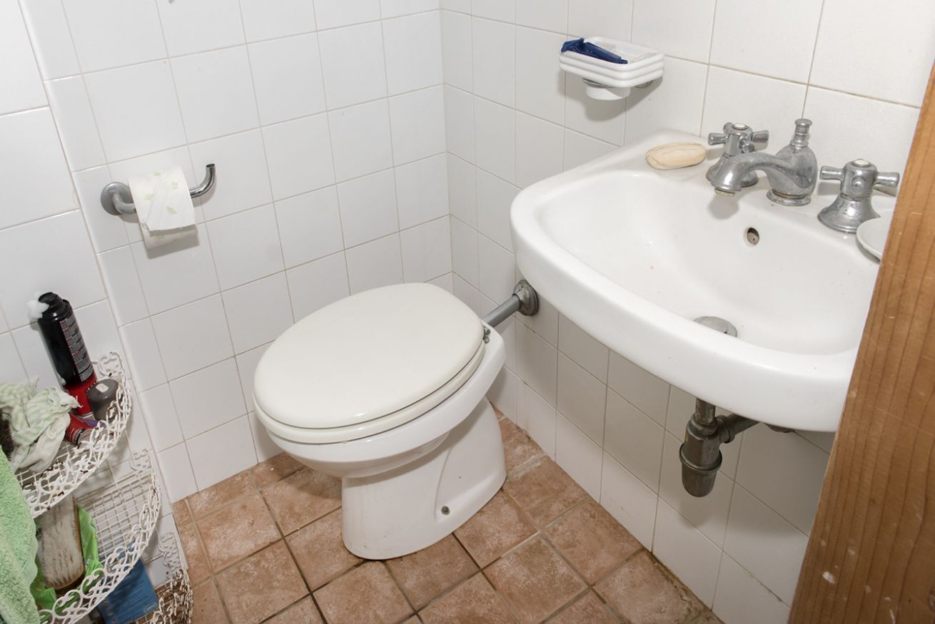 A bathroom with a toilet, sink, and tiled walls.