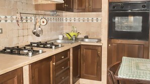 Eine Küche mit Gasherd, Spüle und Backofen, Holzschränken und einem Essbereich mit Tisch.