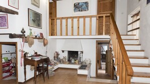 Ein geräumiger Wohnbereich mit einer Holztreppe, einem Kamin und verschiedenen Dekorationselementen.