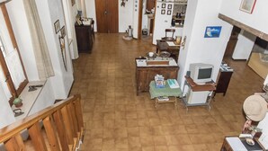 Ein geräumiger Raum mit einer Holztreppe, einem Esstisch mit Stühlen, einem Fernseher und verschiedenen Dekorationen an den Wänden.