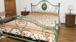 Ein Bett mit floralem Überwurf, ein Holfischschrank und zwei Nachttische mit Lampen.
