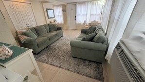 A living room with two green sofas, a small table with decorative items, and a white radiator.