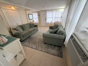 A living room with two green sofas, a small table with decorative items, and a white radiator.