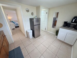 A compact kitchen with a refrigerator, microwave, and a small trash bin.