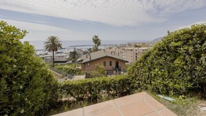 A residential area with a view of the ocean, a palm tree, and a house with a sloped roof. - GuestHost - Amazing studio of 36 sqm, able to accommodate up to 3 people, located on the ground floor of a building in the quiet residential complex of Collina Fiorita. The property boasts a spacious terrace with fabulous views of Porto Sole and the avai (Sanremo)