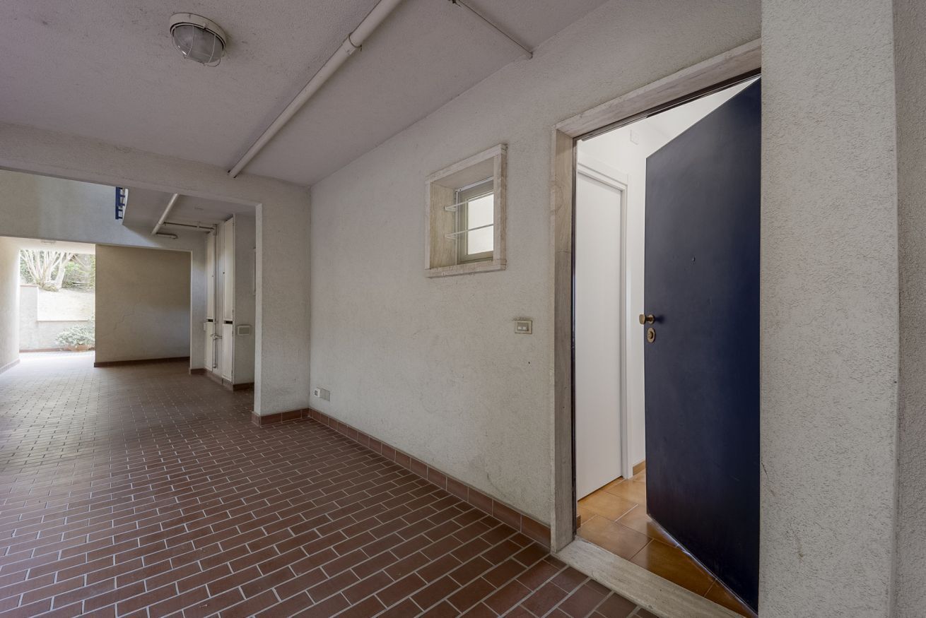 A hallway with a tiled floor, a door, and a window.