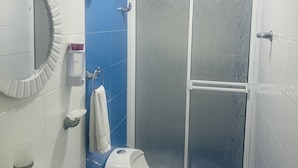 Une salle de bain avec un lavabo blanc, des toilettes et une douche fermée par une paroi de verre.