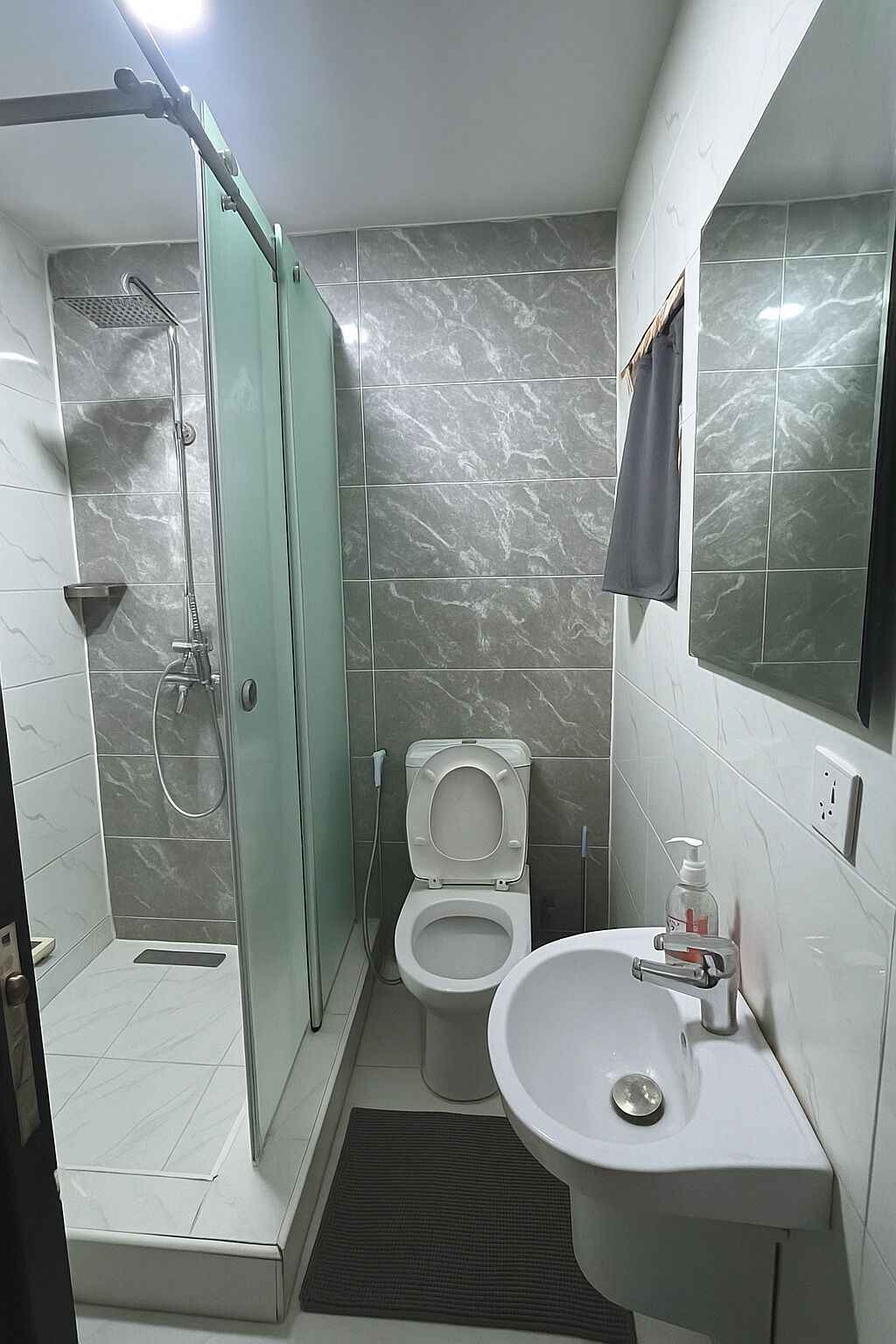 Une salle de bain avec une douche à parois de verre, des toilettes et un lavabo avec un miroir.