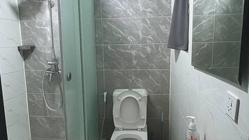 Une salle de bain avec une douche à parois de verre, des toilettes et un lavabo avec un miroir.