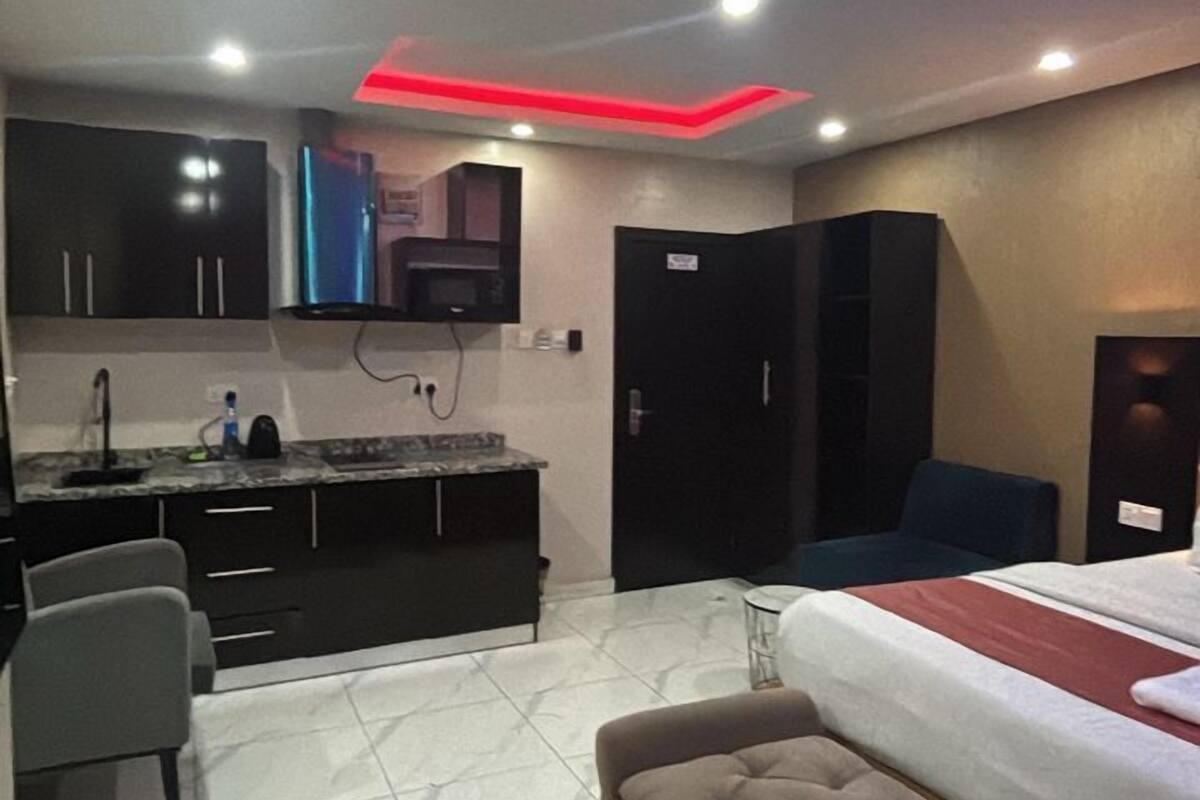 A modern hotel room with a kitchenette, a sofa, and a bed.