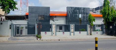 Un edificio amurallado con techo rojo, cerca de seguridad y un bolardo en la acera.