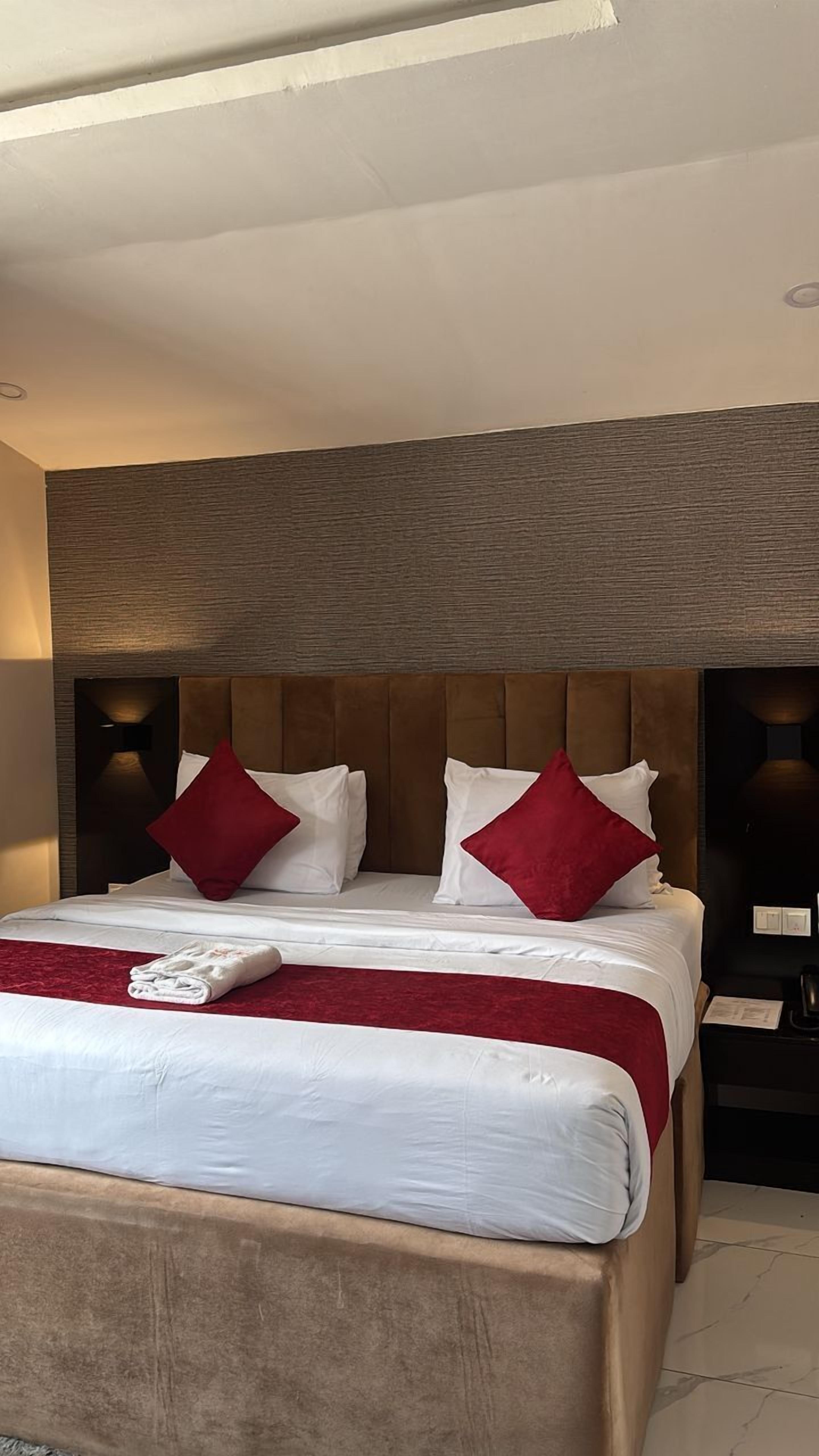 Ein modernes Hotelzimmer mit einem großen Bett, zwei roten Kissen und einem Holzkopfteil.