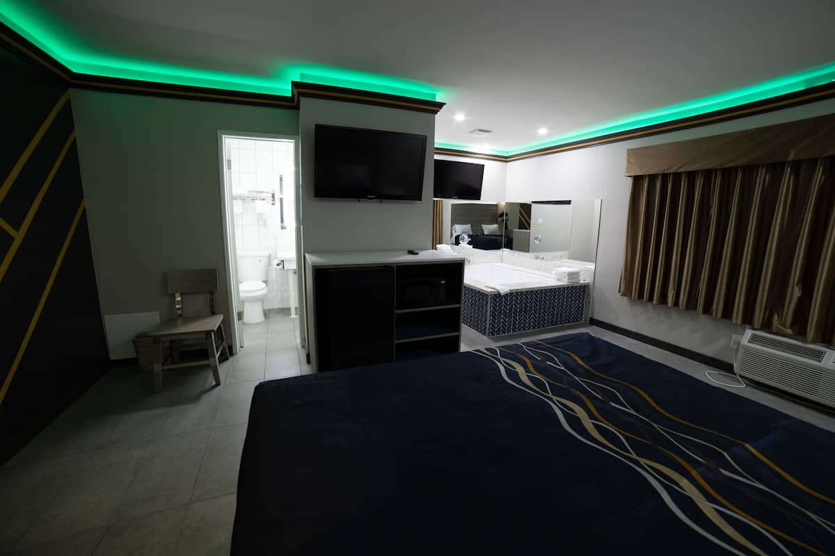 A hotel room with a bed, a TV, a bathroom, and a desk.