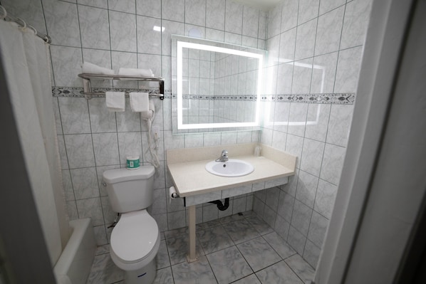 A bathroom with a toilet, sink, and mirror with built-in lighting.