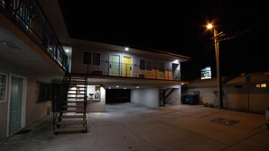 Un motel con un edificio a due piani, un'area parcheggio coperta e una scala che conduce al piano superiore.