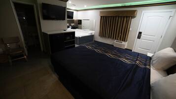A hotel room with a bed, a desk, a television, and a bathroom.