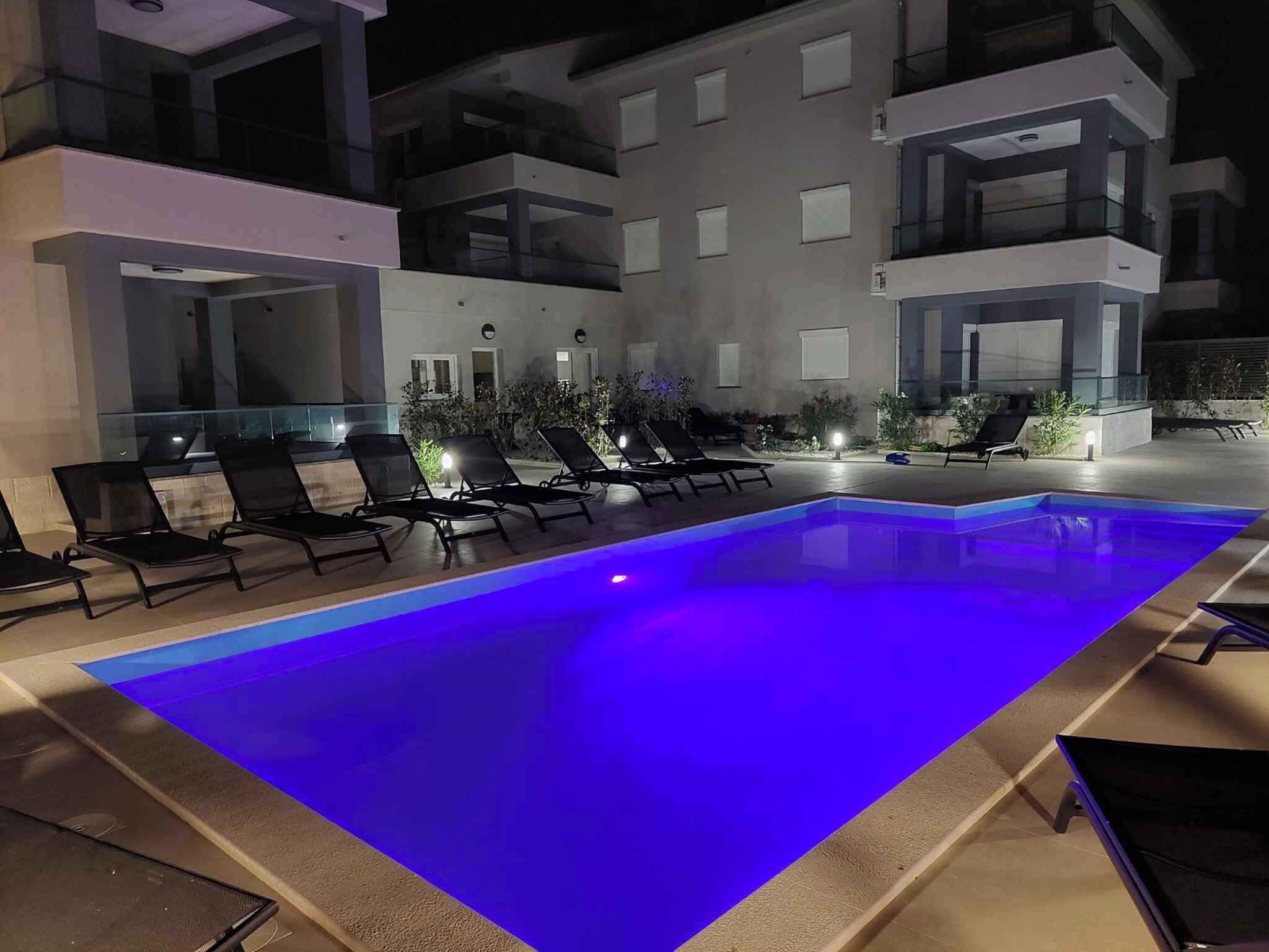 A modern outdoor pool area with lounge chairs and a well-lit pool.