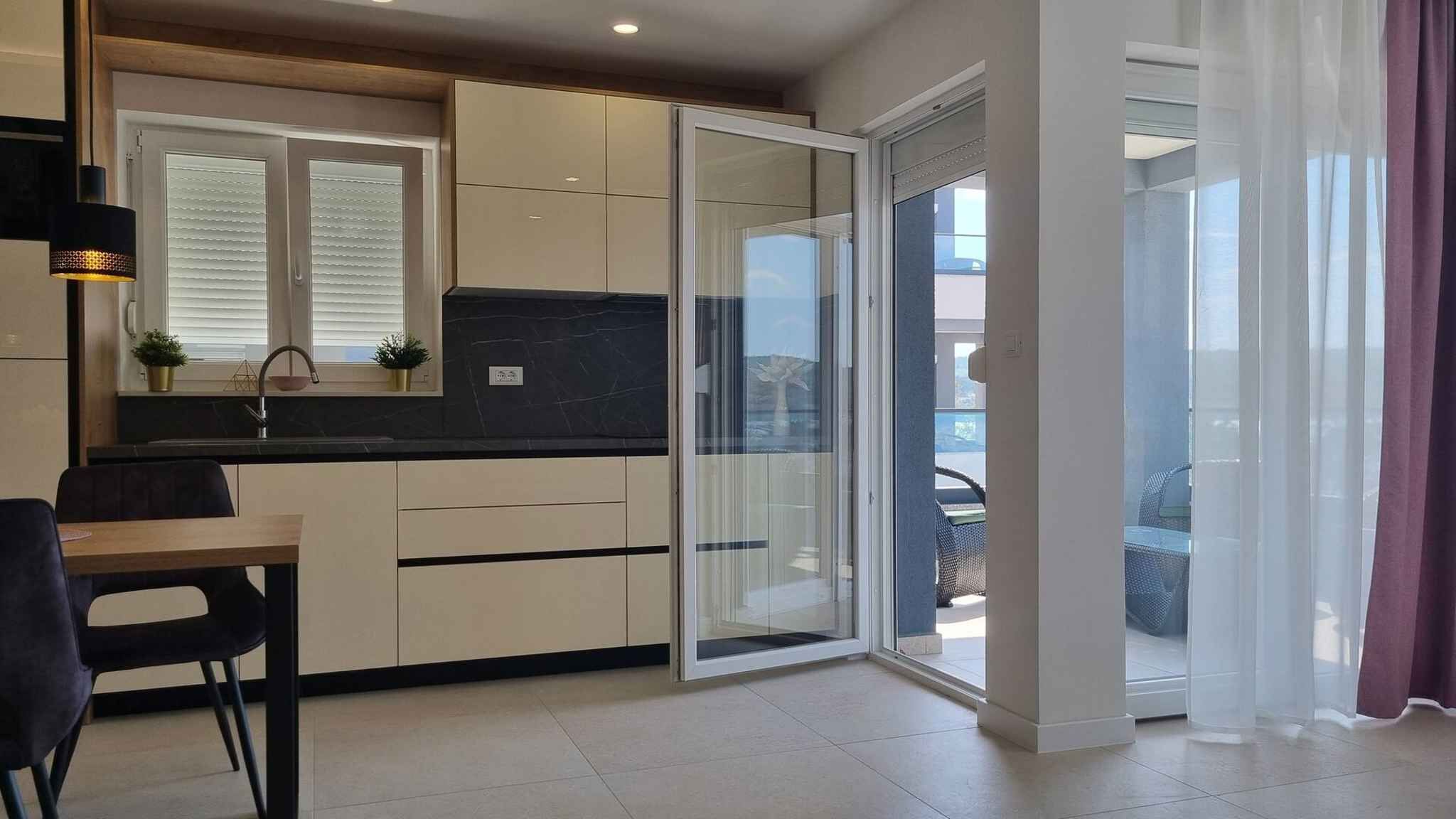 Eine moderne Küche mit Schiebetüren zu einem Balkon, einem Essbereich und einer kleinen Sitzecke.