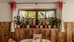 A dining area with a table set for breakfast, including pastries, coffee, and a fruit bowl.