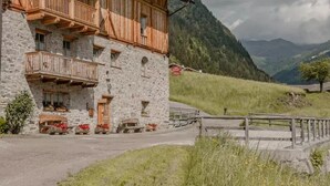 A traditional wooden chalet with stone walls, wooden balconies, and a stone entrance.