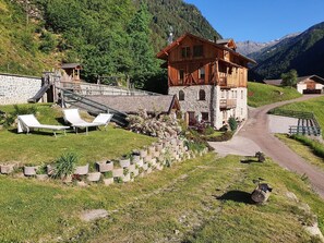 A chalet with a stone foundation, wooden upper structure, and a ski lift nearby.