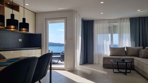 Un salon moderne avec un canapé, un coin repas avec des chaises et une cuisine dotée de luminaires suspendus.