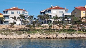 Uma área residencial costeira com casas modernas, varandas e um litoral rochoso.