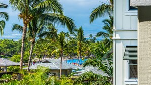 Un resort con palmeras, una piscina y vista al océano.