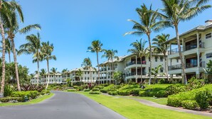 Un resort con edificios de varios pisos, palmeras y un césped cuidado.