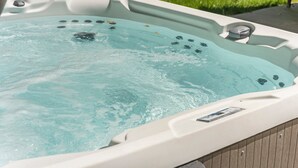 A hot tub with a clear water surface, a control panel, and a label on the side.